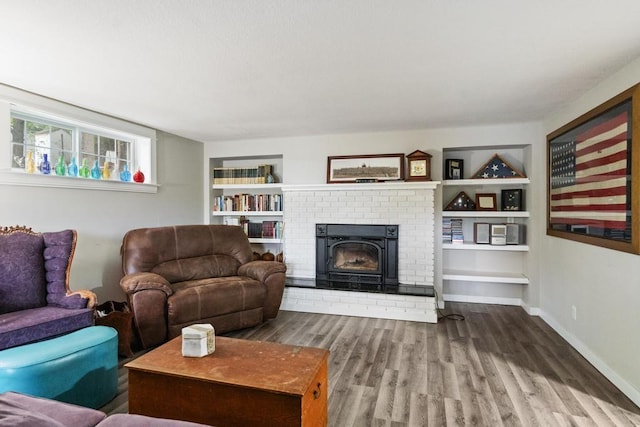 living room with hardwood / wood-style flooring, built in features, and a fireplace