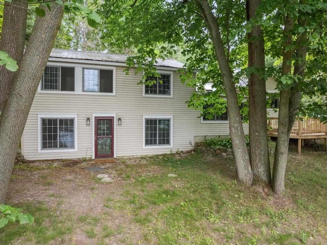 rear view of property featuring a wooden deck and a lawn