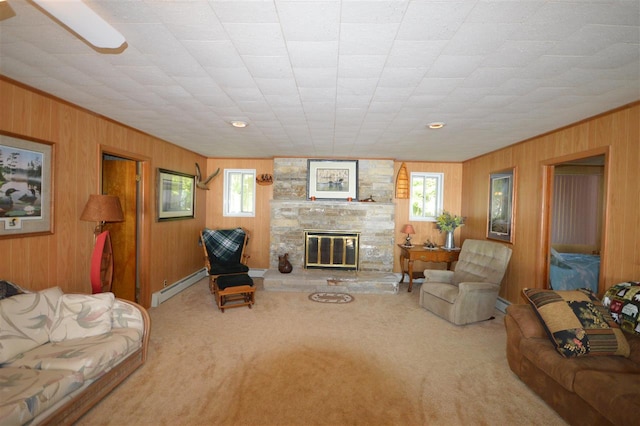 carpeted living room featuring wood walls, a baseboard heating unit, and a stone fireplace