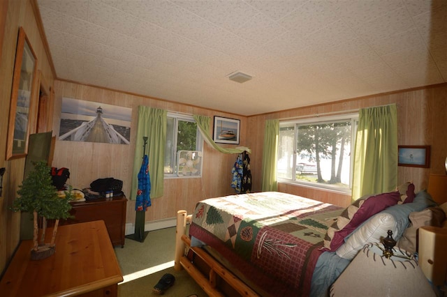 carpeted bedroom with a baseboard heating unit and wooden walls