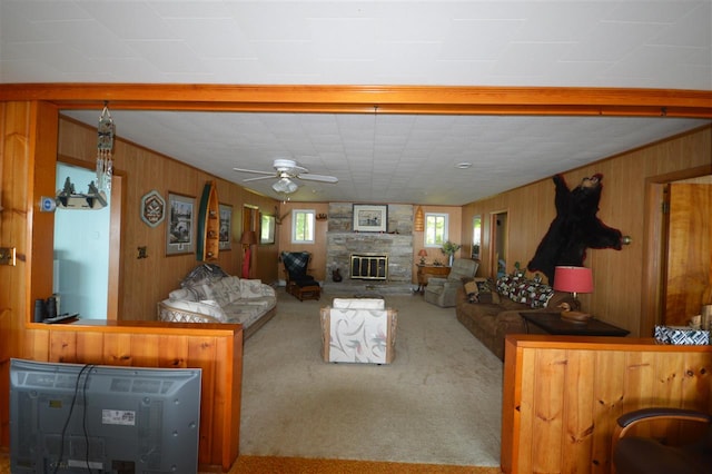 carpeted living room with wood walls, a fireplace, and ceiling fan