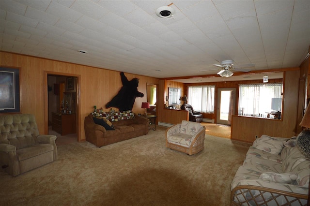 carpeted living room with a baseboard heating unit, ceiling fan, and wooden walls