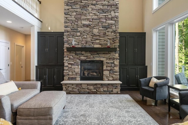 living room with dark wood-type flooring, a fireplace, and a high ceiling