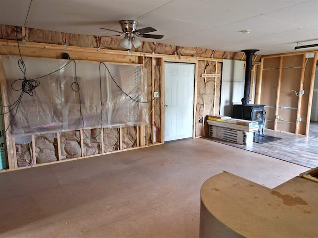 basement featuring ceiling fan and a wood stove