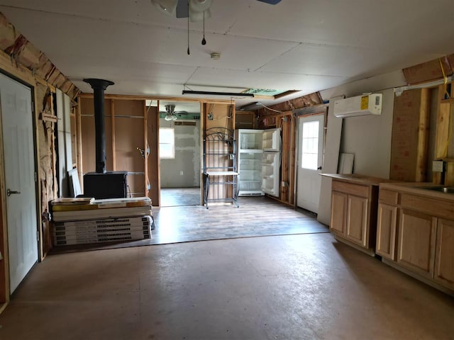 garage with a wall mounted air conditioner, a wood stove, and ceiling fan