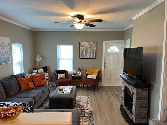 living room with ceiling fan, light wood-type flooring, a fireplace, and ornamental molding