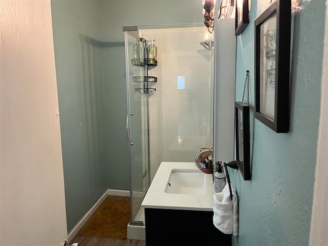 bathroom with a shower with shower door, wood-type flooring, and vanity