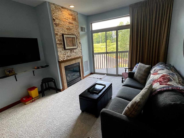 carpeted living room featuring a stone fireplace