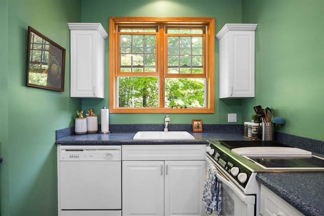 kitchen featuring white appliances, white cabinets, dark countertops, and a sink