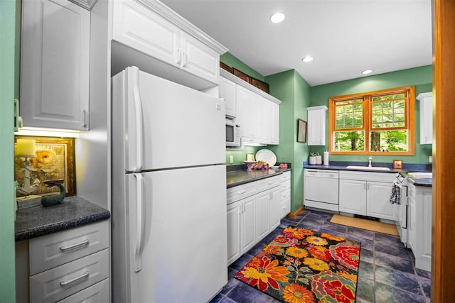 kitchen with white appliances, white cabinetry, and a sink