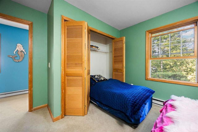 bedroom with a baseboard heating unit, baseboards, carpet floors, a closet, and a baseboard radiator