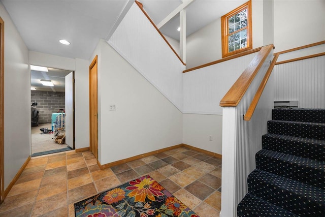 stairway with stone tile floors and baseboards