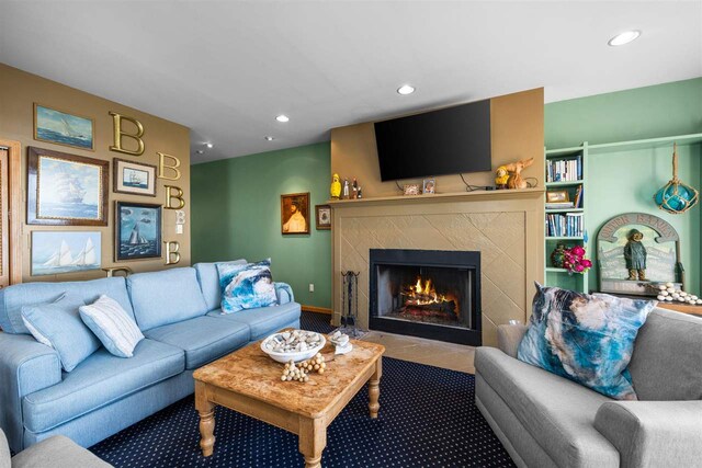 living room with a tiled fireplace and carpet floors