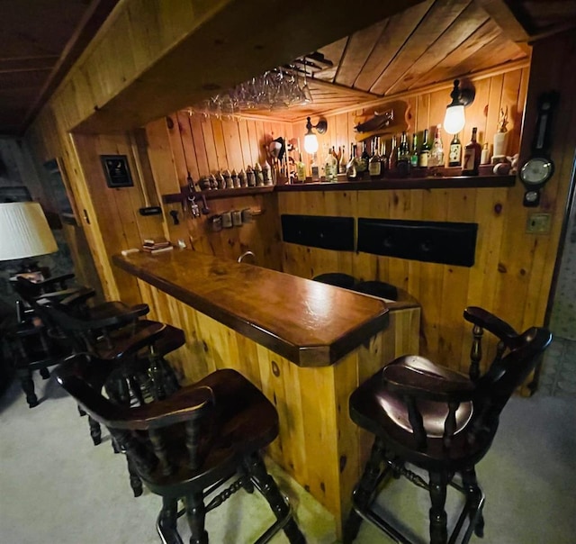 bar with carpet floors, wood walls, and wooden ceiling