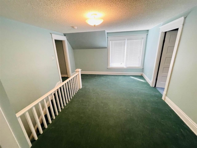 hall with a textured ceiling and dark colored carpet