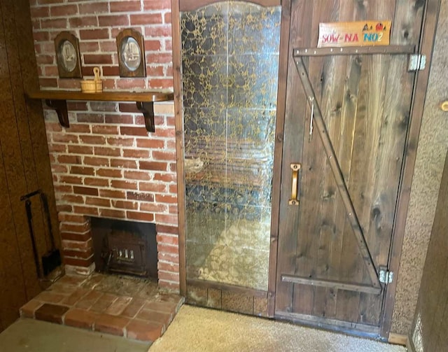 unfurnished living room featuring carpet flooring and a brick fireplace