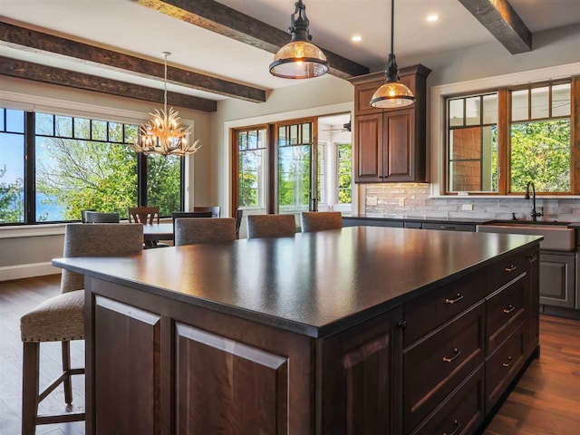 11305 Evergreen Ln, Charlevoix, MI 49720 - kitchen with beamed ceiling, a sink, dark countertops, a breakfast bar area, and dark wood finished floors