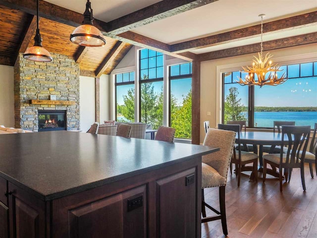 11305 Evergreen Ln, Charlevoix, MI 49720 - dining space featuring a chandelier, dark wood-type flooring, plenty of natural light, a stone fireplace, and wooden ceiling