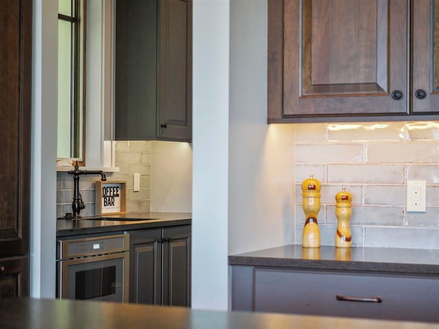 11305 Evergreen Ln, Charlevoix, MI 49720 - kitchen featuring oven, tasteful backsplash, dark brown cabinets, and a sink