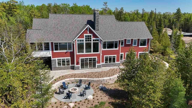 11305 Evergreen Ln, Charlevoix, MI 49720 - back of property featuring an outdoor fire pit, a patio area, a chimney, a sunroom, and stone siding