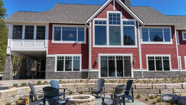 11305 Evergreen Ln, Charlevoix, MI 49720 - rear view of property featuring a fire pit, stone siding, stairway, and a patio