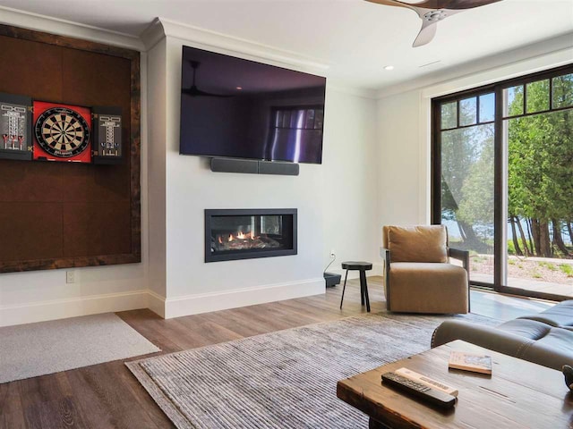 11305 Evergreen Ln, Charlevoix, MI 49720 - living area featuring baseboards, a glass covered fireplace, wood finished floors, ornamental molding, and a ceiling fan
