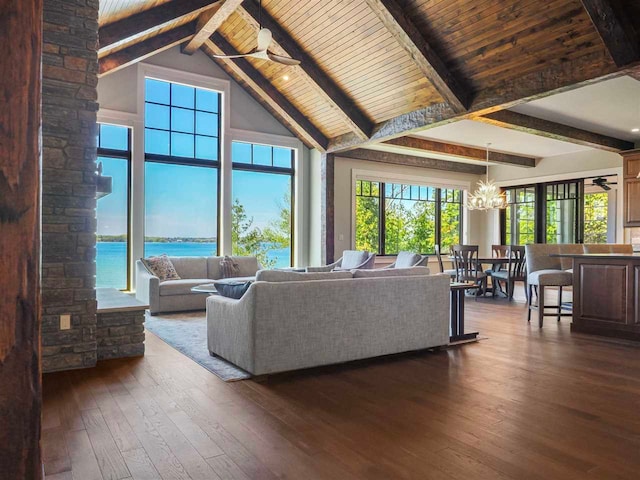 living room featuring beam ceiling, ceiling fan with notable chandelier, hardwood / wood-style floors, and a water view