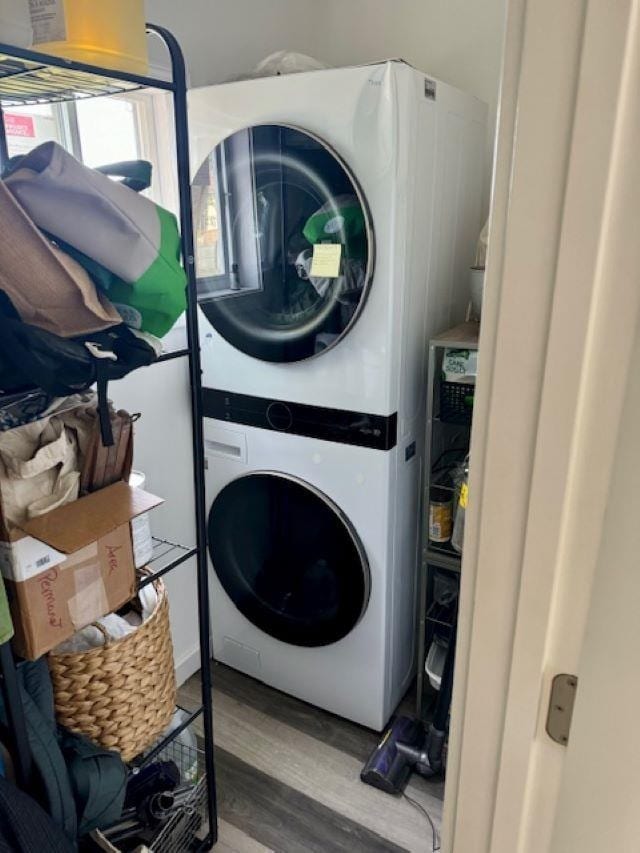 laundry area with hardwood / wood-style floors and stacked washer and dryer