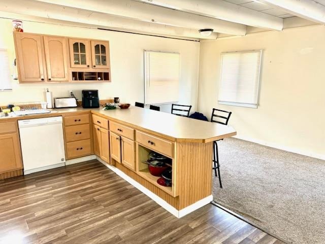 kitchen with kitchen peninsula, beamed ceiling, dark hardwood / wood-style floors, and white dishwasher