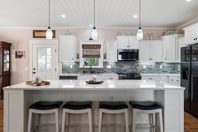 kitchen with hanging light fixtures, stainless steel microwave, black fridge, and a center island