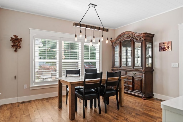 dining area featuring visible vents, crown molding, baseboards, and wood finished floors