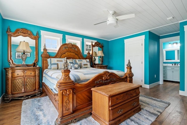 bedroom with ensuite bathroom, a ceiling fan, a sink, baseboards, and hardwood / wood-style flooring