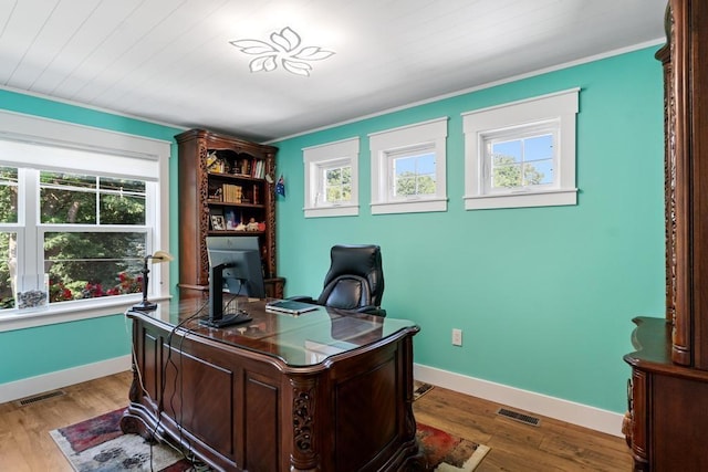 office space featuring ornamental molding, light wood-type flooring, visible vents, and plenty of natural light