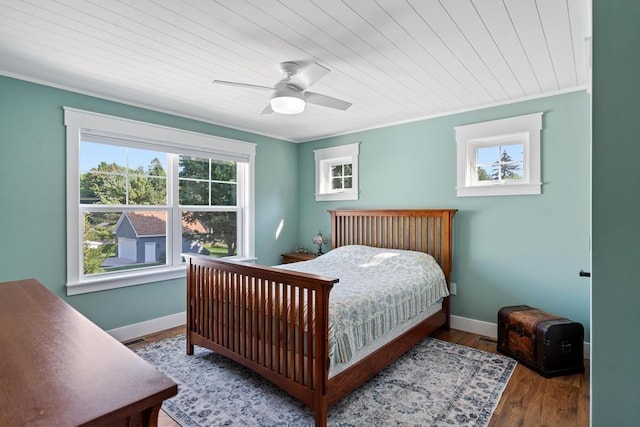 bedroom featuring crown molding, multiple windows, wood finished floors, and baseboards