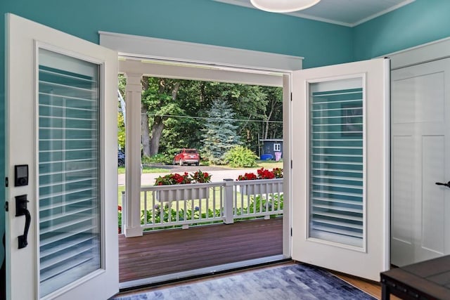 doorway to outside with plenty of natural light, ornamental molding, and dark wood-style flooring