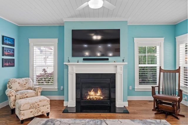 sitting room featuring ornamental molding, baseboards, light wood finished floors, and a fireplace with flush hearth