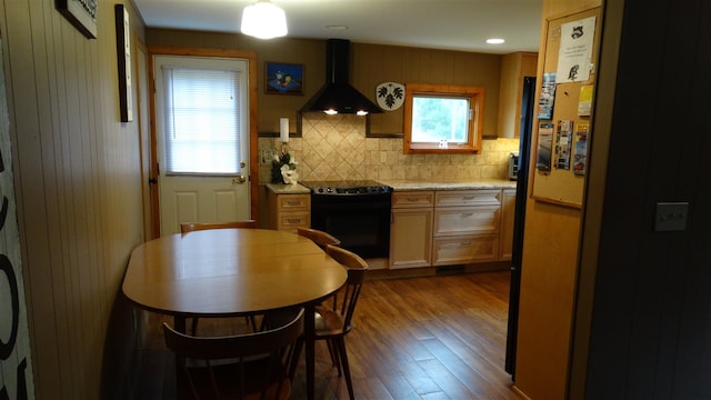 kitchen with black electric range oven, light stone counters, premium range hood, decorative backsplash, and dark hardwood / wood-style floors