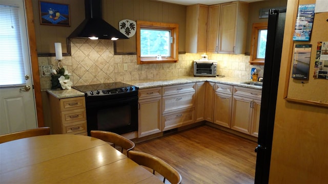 kitchen with black electric range oven, exhaust hood, hardwood / wood-style flooring, and tasteful backsplash