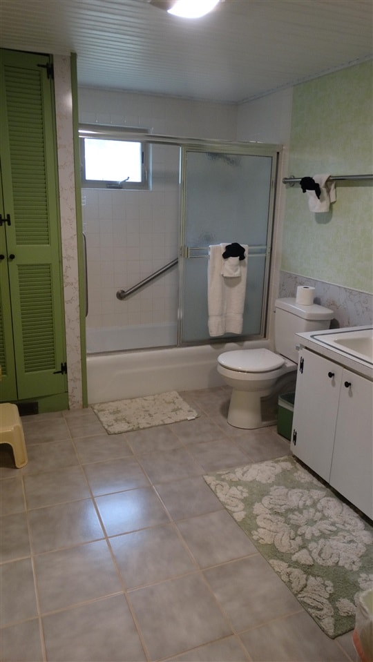 full bathroom with tile patterned floors, toilet, combined bath / shower with glass door, and vanity