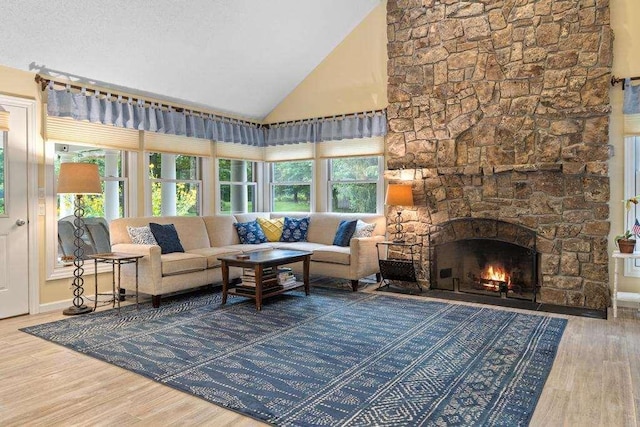645 Woodhill Ct, Harbor Springs, MI 49740 - living room with wood finished floors, baseboards, high vaulted ceiling, a stone fireplace, and a textured ceiling