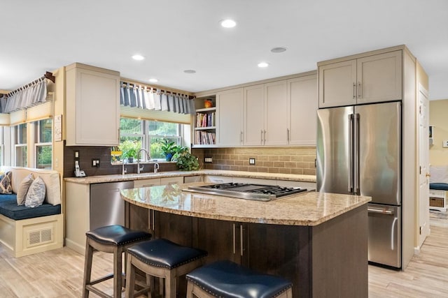 645 Woodhill Ct, Harbor Springs, MI 49740 - kitchen with a sink, light stone counters, a center island, stainless steel appliances, and light wood finished floors