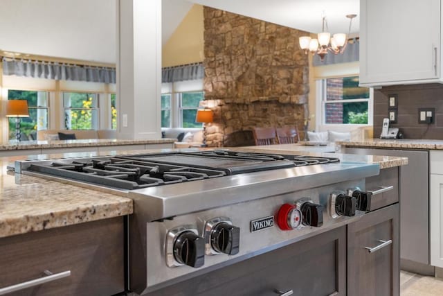 645 Woodhill Ct, Harbor Springs, MI 49740 - kitchen featuring white cabinetry, an inviting chandelier, decorative backsplash, light stone countertops, and stainless steel gas cooktop