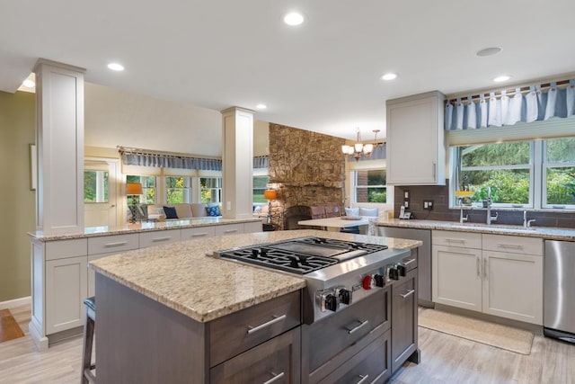 645 Woodhill Ct, Harbor Springs, MI 49740 - kitchen featuring stainless steel gas cooktop, a fireplace, a sink, backsplash, and a center island