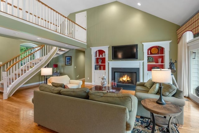 645 Woodhill Ct, Harbor Springs, MI 49740 - living area with high vaulted ceiling, a glass covered fireplace, wood finished floors, stairway, and baseboards