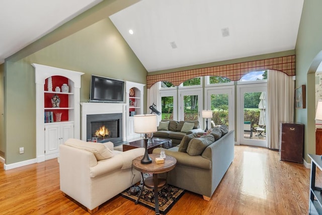 645 Woodhill Ct, Harbor Springs, MI 49740 - living area featuring baseboards, a lit fireplace, light wood-style flooring, and high vaulted ceiling