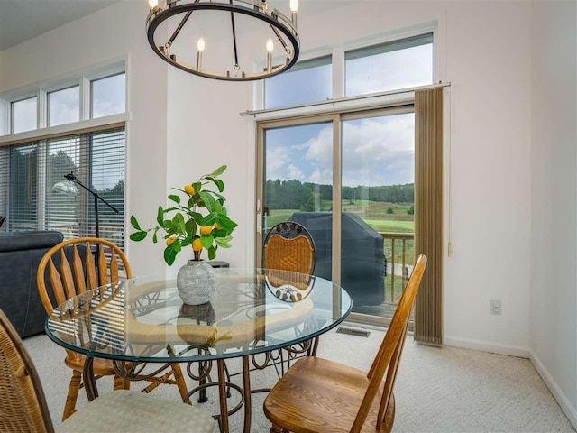 carpeted dining room featuring a wealth of natural light and an inviting chandelier