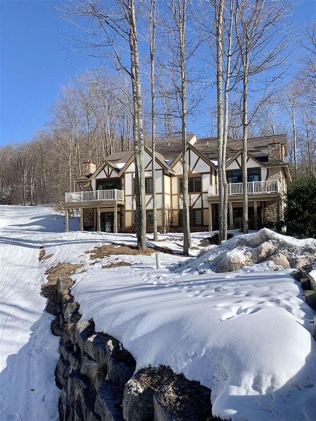 view of front facade featuring a deck, a chimney, and a balcony