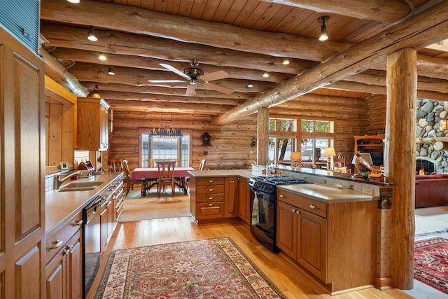 kitchen with light hardwood / wood-style flooring, black appliances, a stone fireplace, rustic walls, and ceiling fan