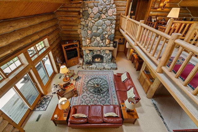 carpeted living room featuring a towering ceiling, log walls, wooden ceiling, and a stone fireplace