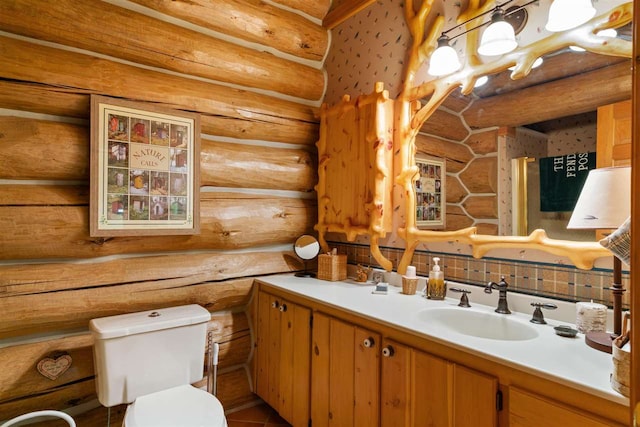 bathroom with log walls, vanity, and toilet